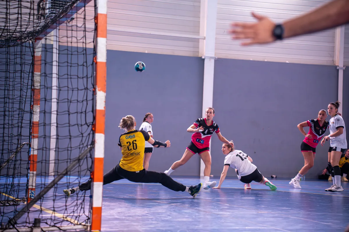 A handball goalkeeper diving to block a shot mid-air