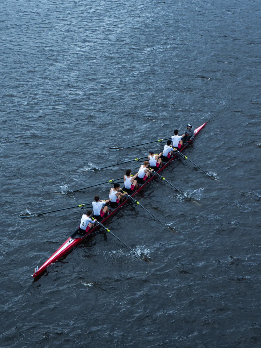 An eight-person rowing crew training on open water, seen from above
