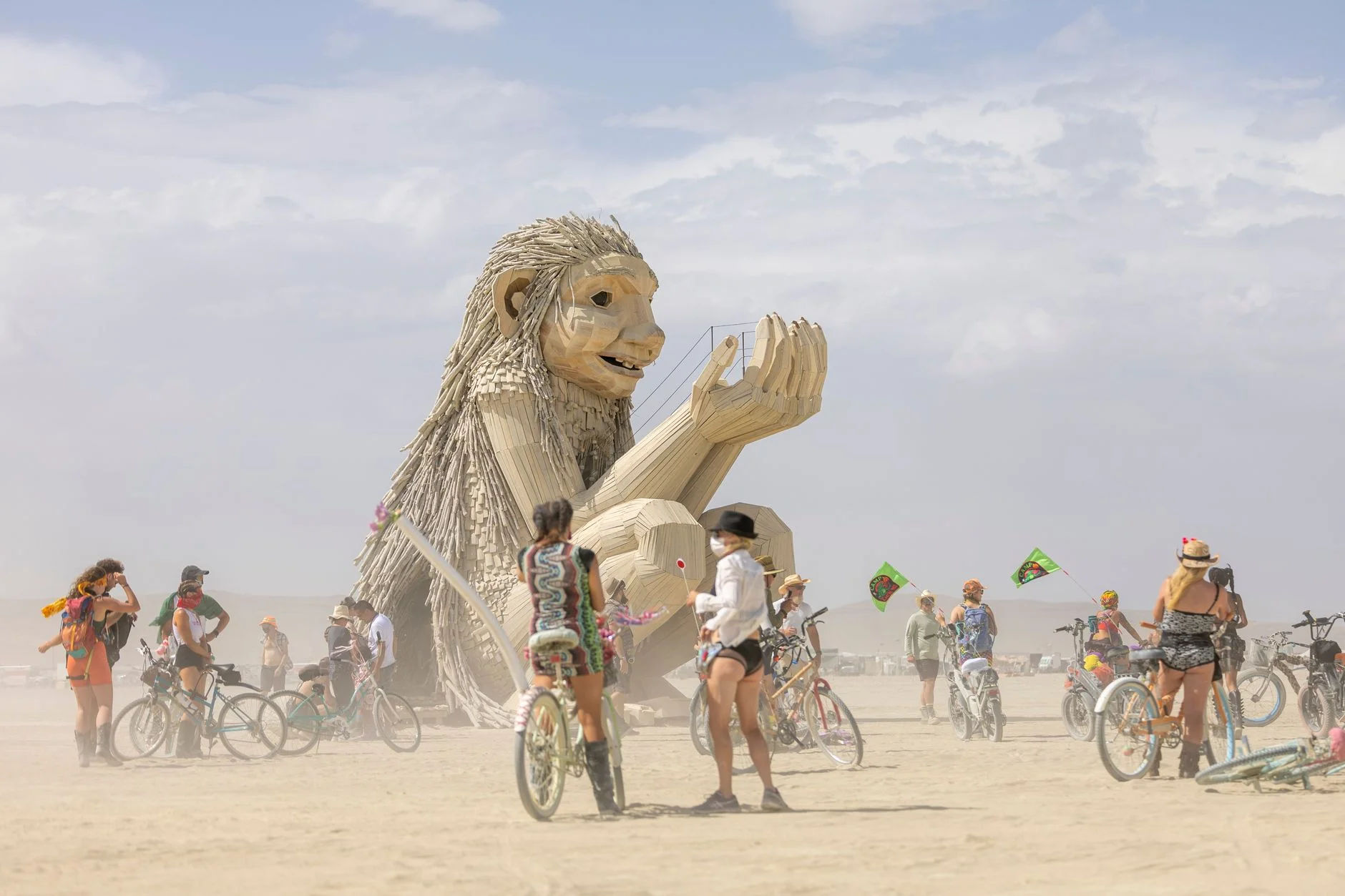 A giant sculpture surrounded by festivalgoers and bicycles at a desert arts festival