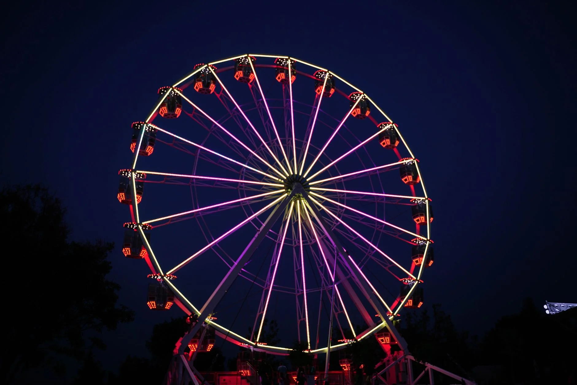 An illuminated fairground ride glowing at night during Oktoberfest