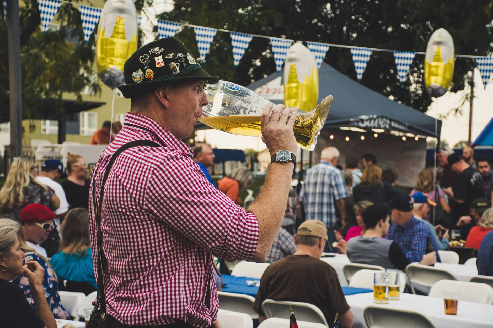 A man raising a large beer stein amid a lively Oktoberfest crowd
