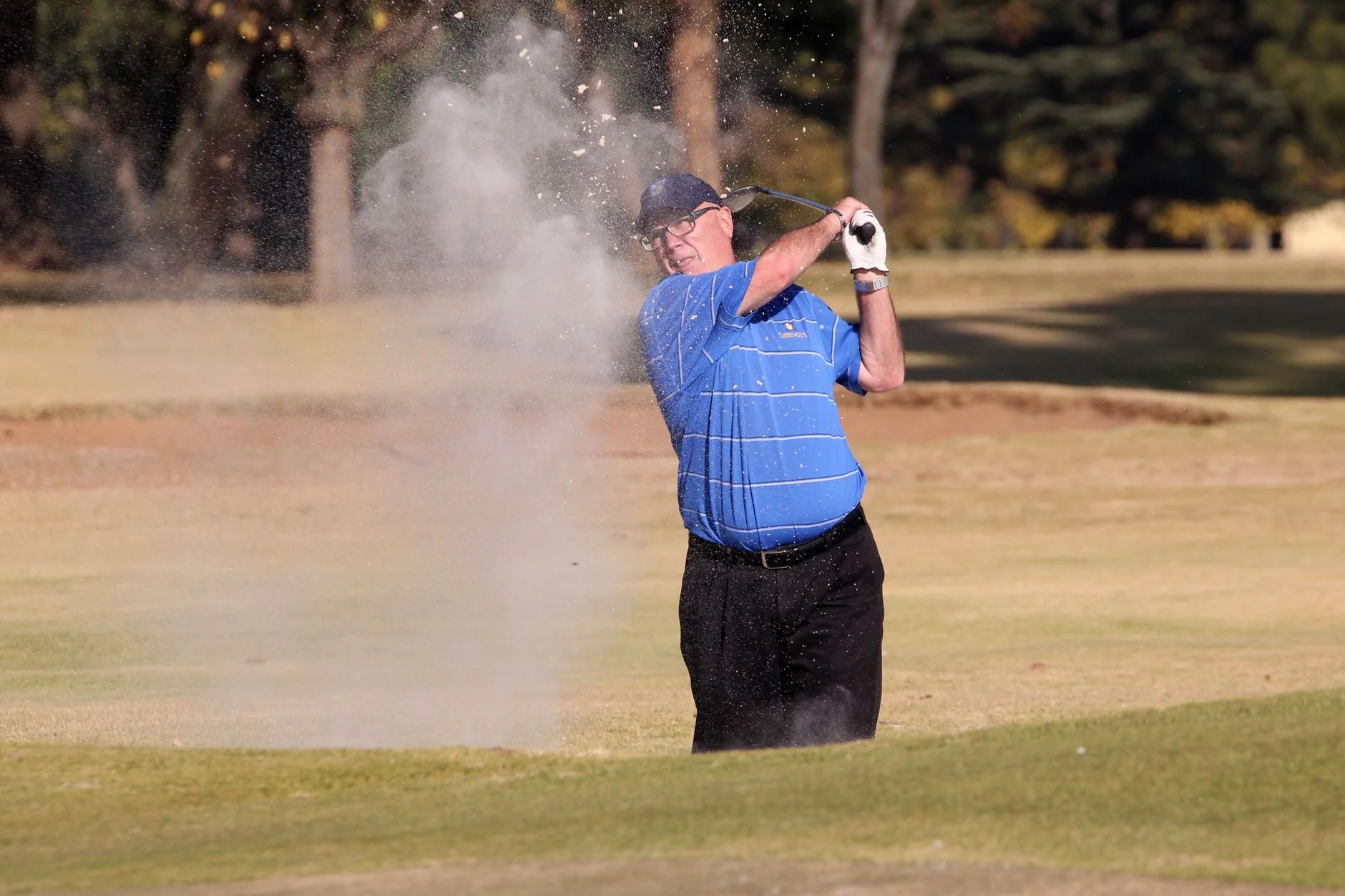 A golfer playing a shot out of a sand bunker