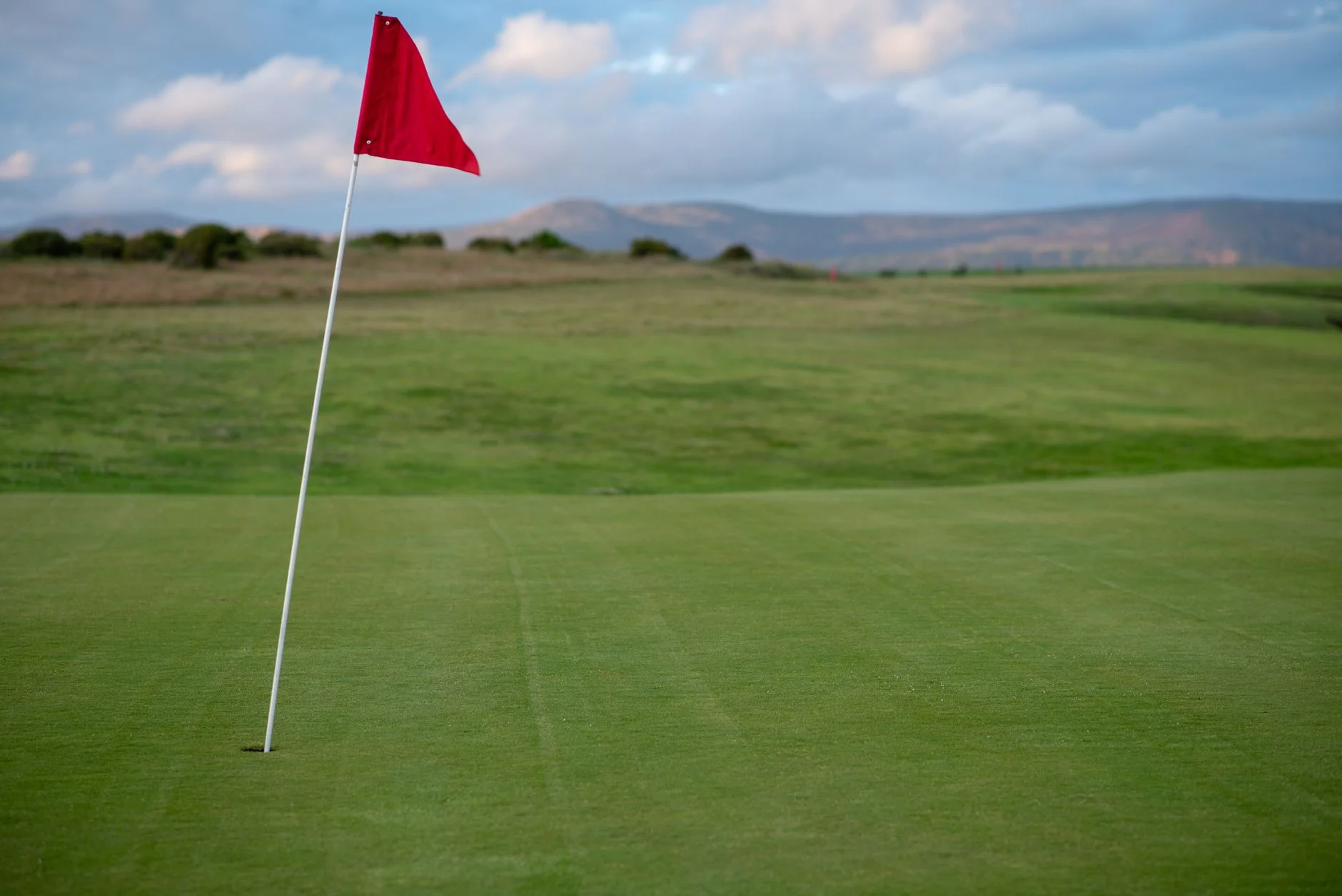 A golf green with a red flag marking the hole