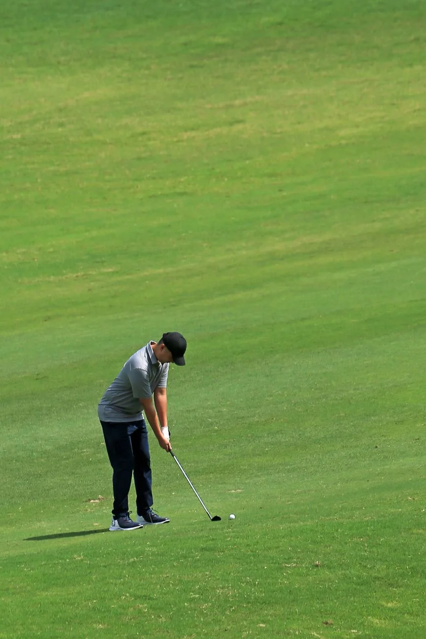 A golfer mid-swing on a sunlit fairway