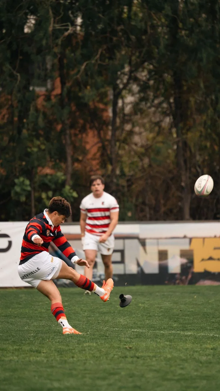 A rugby player mid-kick during an outdoor match