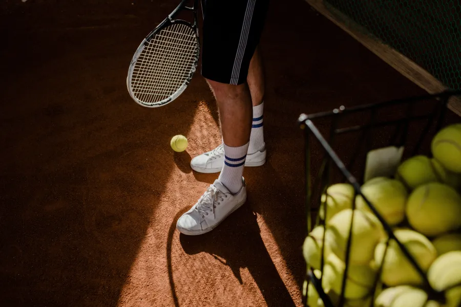 A basket of tennis balls at the edge of a clay court